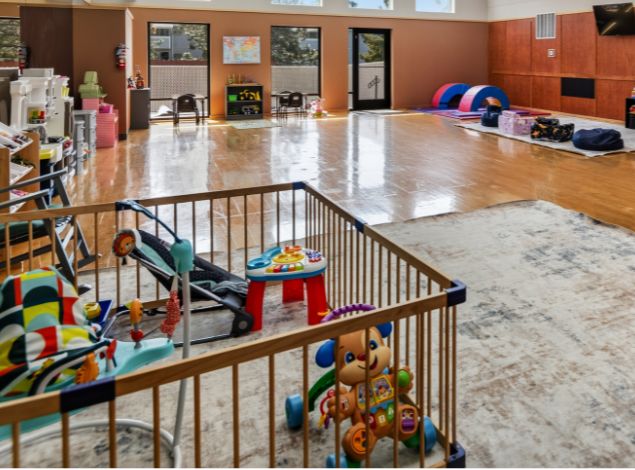 Infant and toddler play area in the Kids Club at Peak Health & Wellness Coeur d'Alene, featuring age-appropriate toys, seating, and open play space.