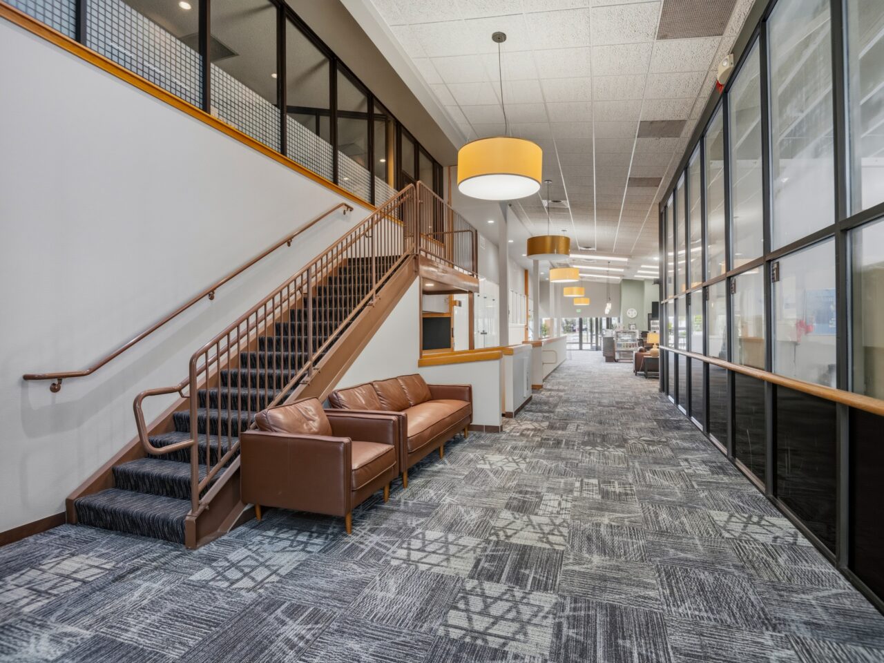 Modern lobby hallway with member seating and staircase inside Peak Health & Wellness Coeur d'Alene.