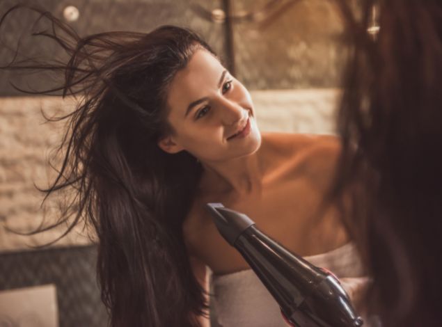 Gym member drying her hair after a workout in a locker room.