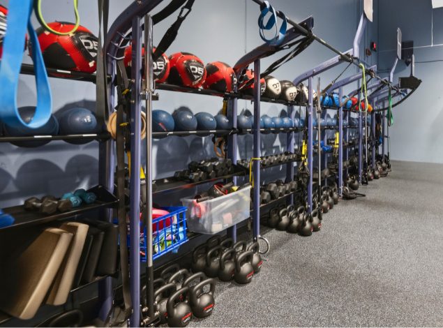 Functional training rack at Peak Health & Wellness Hayden with kettlebells, dumbbells, medicine balls, suspension trainers, and resistance bands.