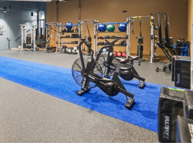 Functional training turf lane with air bike, medicine balls, resistance equipment, and free weights at Peak Health & Wellness Hayden.