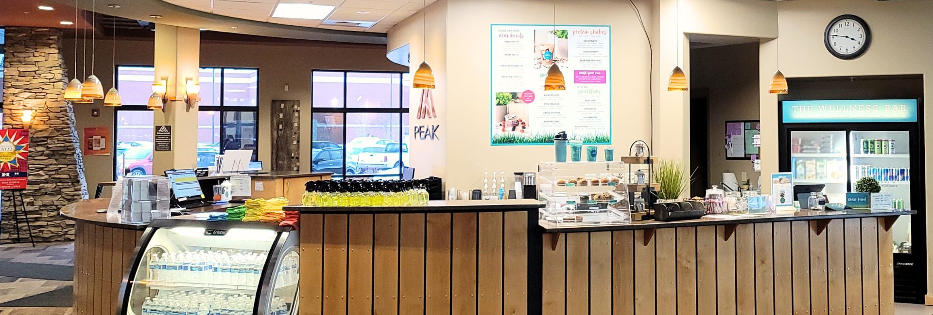 Peak Health & Wellness Hayden juice bar with a digital menu board, fresh drinks, snacks, and The Wellness Bar refrigerator.