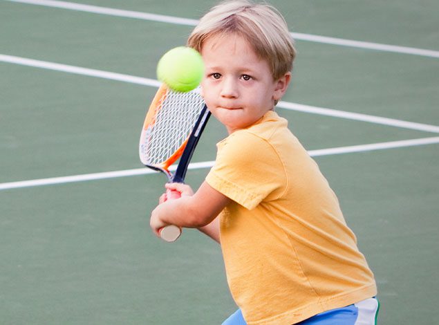 a child is about to hit a tennis ball