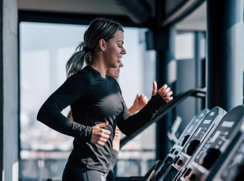 Woman running on a treadmill during a cardio workout at Peak Health & Wellness.