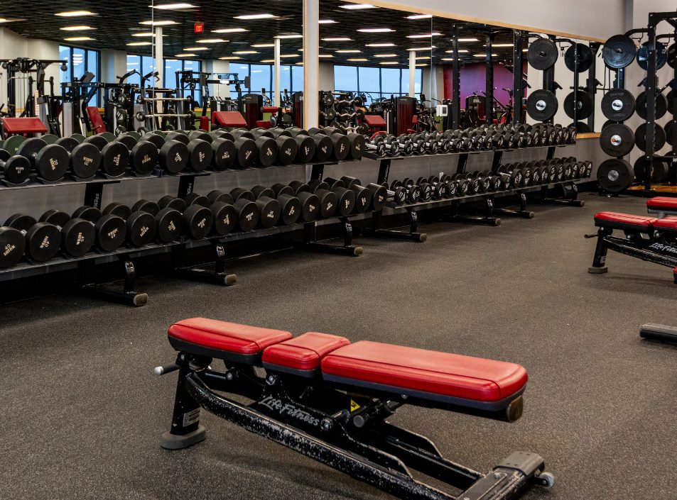 Dumbbell racks, adjustable benches, plate-loaded equipment, and squat racks in the free weights area at Peak Health & Wellness Post Falls.