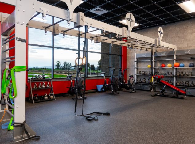 Functional training zone at Peak Health & Wellness Post Falls with training rig, suspension straps, air bikes, kettlebells, medicine balls, and free weights.