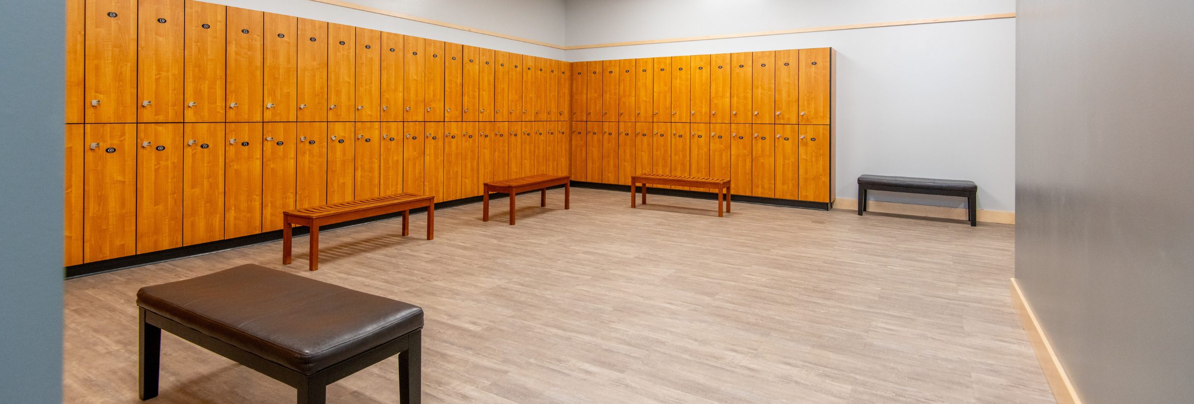 Spacious locker room with wood lockers and benches at Peak Health & Wellness Post Falls.