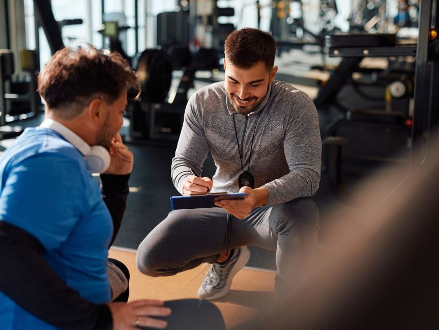 Personal trainer planning a workout with a client at Peak Health & Wellness