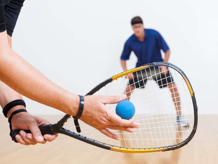 Man preparing to serve during indoor racquetball game at Peak Health & Wellness