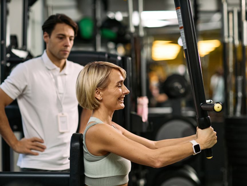 Senior woman strength training with guidance from a personal trainer at Peak Health & Wellness